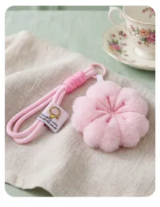Primer plano del tierno llavero de peluche de flor de cerezo rosa sobre tela de lino.