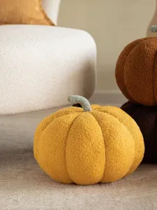 Detalle de cojín de calabaza de felpa suave con tela texturizada y tallo verde realista.