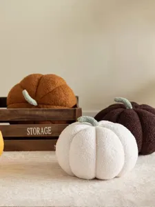 Detalle de cojín de calabaza de peluche acogedor, tela texturizada suave, decoración de hogar cálida.