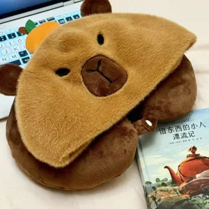 Vista detallada de la almohada de viaje de peluche capibara marrón con capucha, tela muy suave.