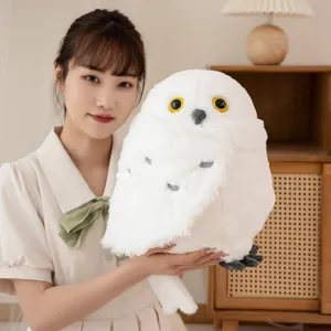 Primer plano del tierno peluche de búho blanco sostenido en un entorno cálido y acogedor.