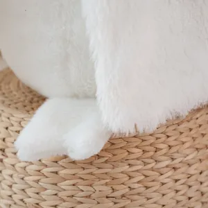 Primer plano detallado de un suave peluche blanco sentado en una cesta tejida.