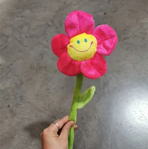 Primo piano di un simpatico giocattolo di fiore smiley in peluche con petali rosa e stelo.