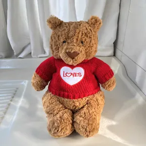Süßer Plüsch Teddybär im roten Strickpullover mit Herzstickerei als schönes Spielzeug.