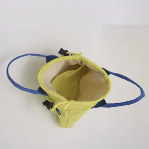 Vue détaillée du sac seau à cordon vert clair avec anses bleues et poche intérieure.