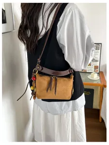 Retro suède schoudertas detailweergave met bruin design en chique hangende bedels.