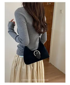 Vista detallada del bolso de hombro negro retro con elegante hebilla metálica y textura.
