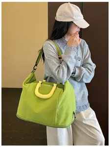 Detailed view of large capacity green travel duffel bag with yellow handle and shoulder strap.