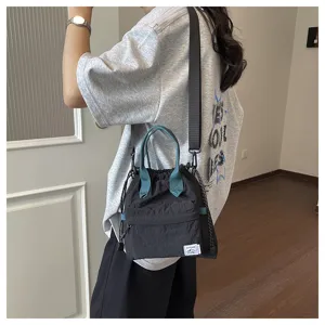 Vue détaillée du sac seau minimaliste en nylon noir avec poignées et sangle vertes.