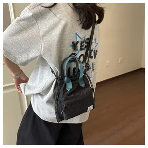 Sac seau noir décontracté avec poignées vertes, bandoulière élégante et pratique.