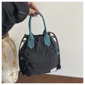 Gros plan détail du sac seau noir avec poignées vertes et cordon de serrage casual.