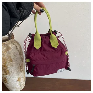 Vue rapprochée détaillée du sac seau bordeaux à cordon avec poignées vert lime et poche.