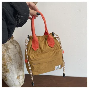 Gros plan sur le sac seau marron élégant doté de poignées orange et d'une fermeture à cordon.