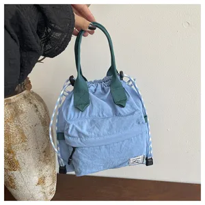 Vue détaillée du sac seau bleu à cordon avec poignées vertes et une petite poche avant.