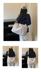 Detail view of large capacity solid color travel shoulder bag with purple handle grip for daily use.