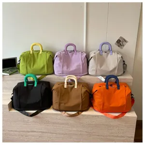 Large capacity solid color travel duffel bag with stylish contrast handles and cross body strap.