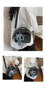 Details of washed denim Boston bag showcasing fabric texture, metal hardware and chic charms.