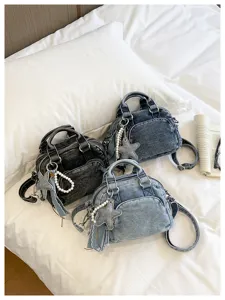 Denim boston bag detail view showcasing star charms and pearl straps on white bed.