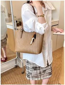 Vista detallada del elegante bolso de hombro tejido marrón con bonito colgante de cuentas de madera.