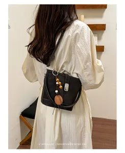 Sac seau noir style rétro de niche détail avec pendentif perles en bois et serrure métal.
