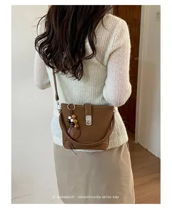 Vue détaillée du sac seau marron rétro chic doté d'un fermoir en métal et d'un charmant pendentif.