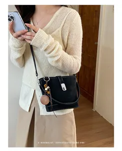 Sac seau noir rétro minimaliste avec poignée et charmant pendentif en perles de bois.