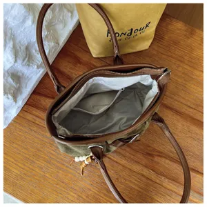 Sac porté épaule rétro vert avec poignées en cuir et pendentif perlé pour le trajet quotidien.