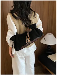 Detailed view of the black canvas shoulder bag with brown leather trim and heart charm.