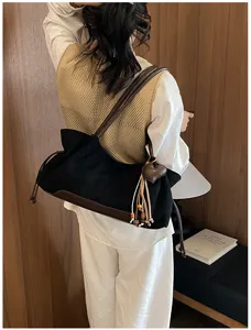 Detailed shot of a stylish black shoulder bag with brown trim and heart tassel charm.