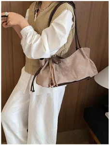 Detail shot of retro suede underarm shoulder bag with elegant tassel and contrast trim.