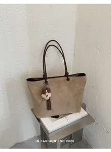 Details of the brown suede tote bag with comfortable handles and cute bear charm.