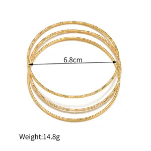 Detailaufnahme minimalistischer mehrlagiger goldener Armreifen aus edlem Titanstahl.