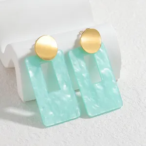 Pendientes geométricos elegantes con tachuelas redondas doradas y colgantes de resina verde menta.