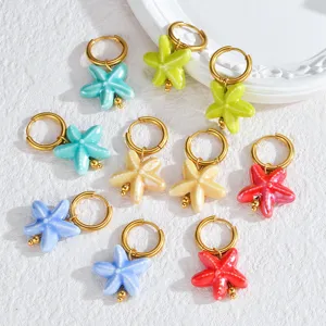 Detailed view of colorful ceramic starfish hoop earrings with shiny gold rings, vibrant design.