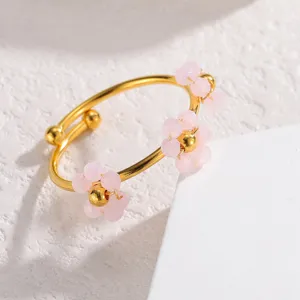 Nahaufnahme des goldenen Edelstahloffenrings mit süßem rosa perlenbesetzten Blumendesign.