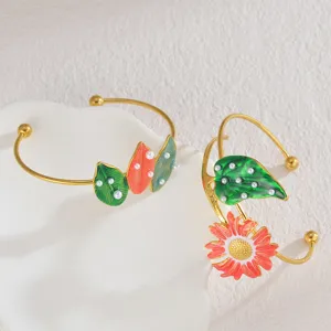 Dettaglio in primo piano del bracciale aperto in smalto con foglia e girasole e perle.