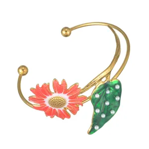 Bracciale rigido aperto dorato con girasole smaltato colorato e foglia decorata con perle.