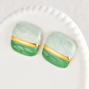 Primo piano di orecchini quadrati in marmo verde e bianco con dettaglio di barra dorata.