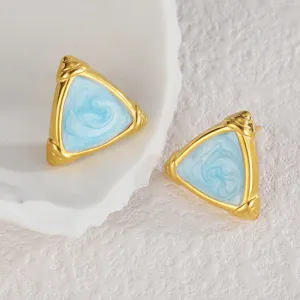 Detailansicht minimalistischer dreieckiger Ohrringe mit Goldrand und blauem Marmordesign.
