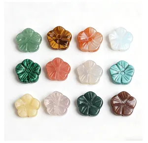 Detail view of various carved natural stone plum blossom flower charms for DIY jewelry making.