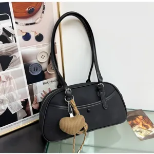 Detailed view of the black underarm shoulder bag with woven heart pendant and sleek design.