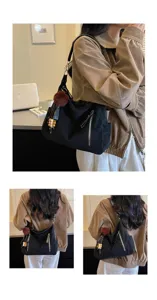 Detalle del elegante bolso de hombro negro con pompón de pelo y un estilo casual chic.