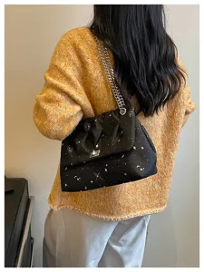 Détail rapproché d'un sac porté épaule noir stylé avec imprimé étoiles et chaîne argent.