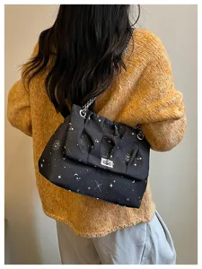 Détail de sac porté épaule noir chic avec imprimé étoiles et bandoulière chaîne métallique.