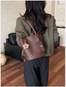 Detailed view of the dark brown woven shoulder tote bag with cute floral pendant accessory.