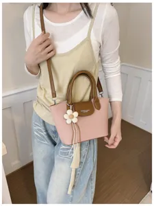 Close-up detail of the stylish pink and brown cross-body handbag with floral charm.