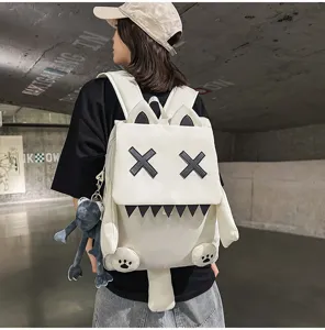 Detail view of the cute cartoon white canvas backpack featuring XX eyes and plush animal pendant.