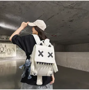 Cute cartoon monster backpack with X eyes and plush pendant, stylish student travel bag for daily use.