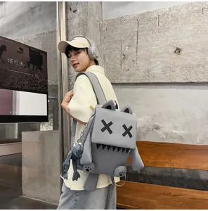 Detail view of grey monster backpack featuring XX eyes plush design and cute doll pendant.