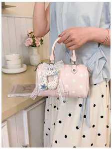 Pink polka dot barrel bag detail featuring sweet musical note charm and elegant lace bow.